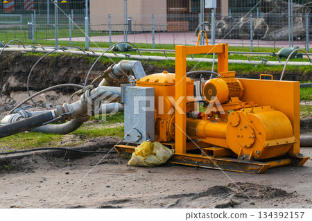 Industrial dewatering pump with hoses operating at construction site for groundwater removal Industrial dewatering pump with hoses operating at construction site for groundwater removal 134392157