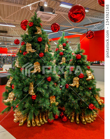 Christmas trees decorated with gold boots and red ornaments in festive holiday display at shoe store 134392168