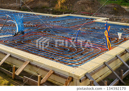 Underfloor heating pipes installed on reinforced foundation grid during modern home construction Underfloor heating pipes installed on reinforced foundation grid during modern home construction 134392170