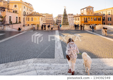 Woman walking with dog toward festive city square in Rome during holiday season 134392349