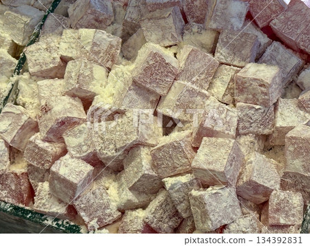 Beige Turkish delight cubes covered in fine powder forming a dense confectionery background. Minimal color palette, tactile surface, classic sweetness, and traditional dessert simplicity emphasized 134392831