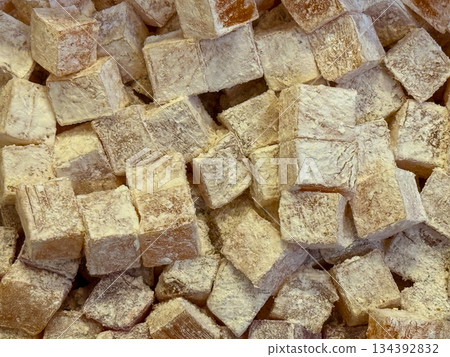 Beige Turkish delight cubes covered in fine powder forming a dense confectionery background. Minimal color palette, tactile surface, classic sweetness, and traditional dessert simplicity emphasized 134392832
