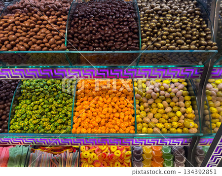 Rows of glossy chocolate style nuts displayed under decorative lighting in a market stall in bazaar Istanbul. Sensory richness, indulgent mood, visual density, and confectionery attraction through Rows of glossy chocolate style nuts displayed under decorative lighting in a market stall in bazaar Istanbul. Sensory richness, indulgent mood, visual density, and confectionery attraction through 134392851