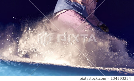Snowboarder Carving a Turn at High Speed, Sending up a Spray of Snow in the Mountains 134393234