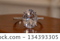 Beautiful White Sapphire Ring Displayed on Wooden Surface With Soft Lighting Highlights 134393305