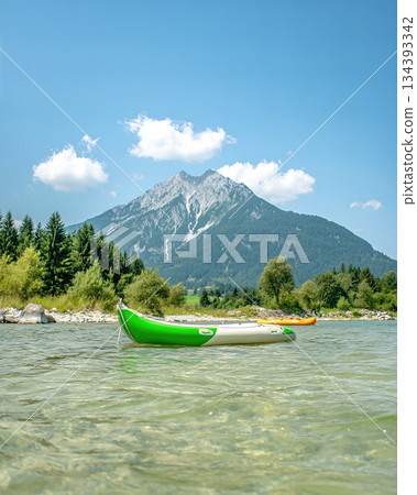 Kayaks Floating on Calm Water With Mountains in the Background During a Sunny Day Kayaks Floating on Calm Water With Mountains in the Background During a Sunny Day 134393342