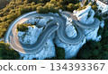 Winding Asphalt Road Curves Through Mountains With Lush Greenery Surrounding Rocky Cliffs 134393367