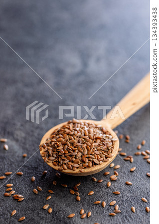 Linseed or flaxseed. Healthy flax seed on wooden spoon on black table. 134393438