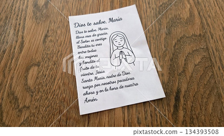 Spanish prayer text with illustrated woman in prayer on wood surface Spanish prayer text with illustrated woman in prayer on wood surface 134393508