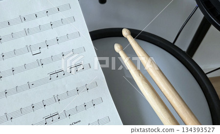 Music practice with drum sticks and sheet music for percussion enthusiasts. International Music Day. Rock-n-Roll Day Music practice with drum sticks and sheet music for percussion enthusiasts. International Music Day. Rock-n-Roll Day 134393527