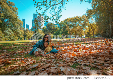 Joyful and Beautiful Moments in Autumn A Mother and Child in a Leafy Park 134393609