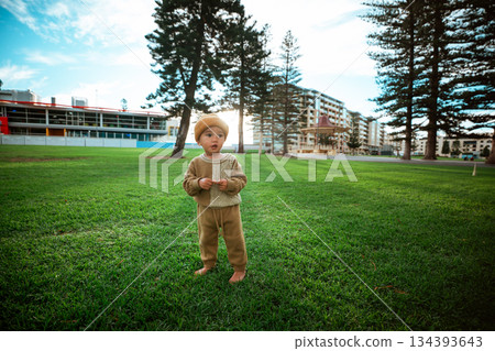 A Happy Child Joyfully Playing in the Park Surrounded by Grass and Trees 134393643