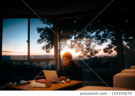 Young Person Working on Laptop During Sunset in Modern Indoor Space Young Person Working on Laptop During Sunset in Modern Indoor Space 134393670
