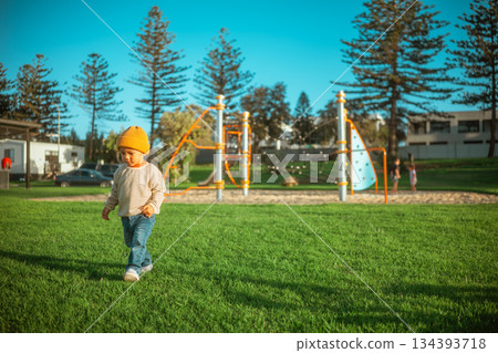 child exploring outdoors, small toddler explores grassy park with pine trees and families child exploring outdoors, small toddler explores grassy park with pine trees and families 134393718