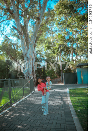 parent gently embraces child on park path, casual walk with bonding between parent parent gently embraces child on park path, casual walk with bonding between parent 134393786