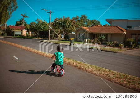child explores neighborhood on scooter, young child enjoying scooter ride on quiet street child explores neighborhood on scooter, young child enjoying scooter ride on quiet street 134393800