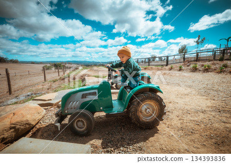 A Child Enjoys Riding a Colorful Toy Tractor on a Beautiful Farm A Child Enjoys Riding a Colorful Toy Tractor on a Beautiful Farm 134393836