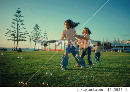 A group of children delightfully enjoying playing with bubbles in the park A group of children delightfully enjoying playing with bubbles in the park 134393844