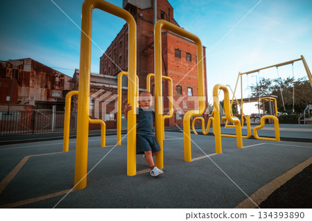 youthful child leaning on yellow railing beside brick building during evening hours youthful child leaning on yellow railing beside brick building during evening hours 134393890