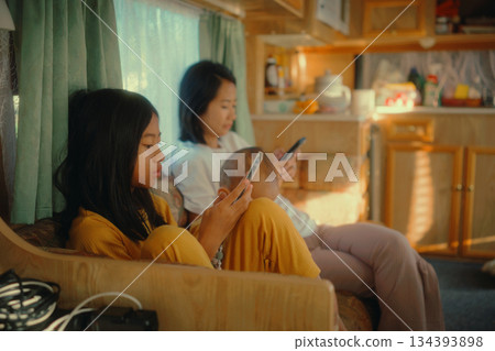 Enjoying a Cozy Family Moment Together in a Vintage RV with Smartphones 134393898