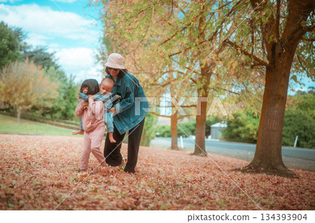 A Family Joyfully Enjoying a Colorful Autumn Day in a Leafy Park 134393904