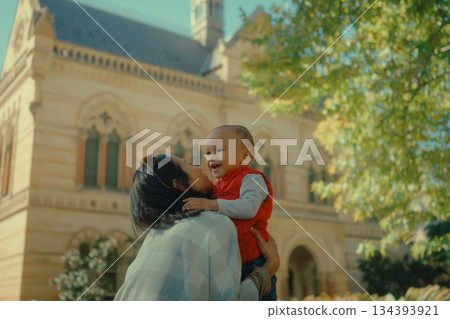 A Joyful Mother and Her Baby Embrace Happily in a Beautiful Outdoor Setting A Joyful Mother and Her Baby Embrace Happily in a Beautiful Outdoor Setting 134393921