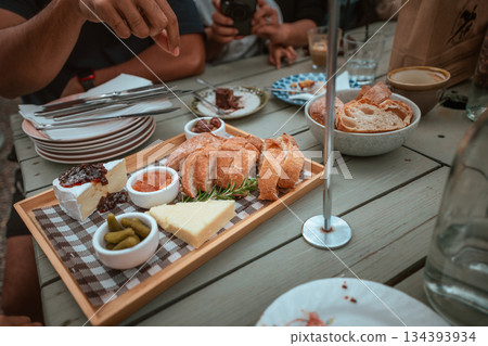 Gourmet Sharing Platter with Bread, Cheese, and Dips at a Dining Table 134393934