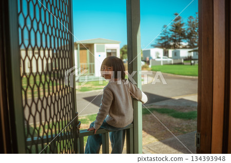 child observes park scene quietly, child looking through doorway at tranquil park scene 134393948