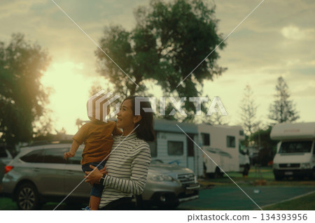 A Serene Family Moment Captured Outdoors During a Beautiful Sunset with a Child 134393956