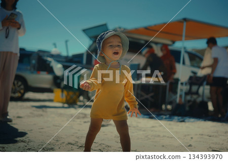 A Joyful Baby is Happily Playing on the Beach in Bright Summer Sunshine A Joyful Baby is Happily Playing on the Beach in Bright Summer Sunshine 134393970