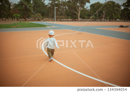 young child on court, toddler in helmet moving playfully in contemporary urban sports 134394054