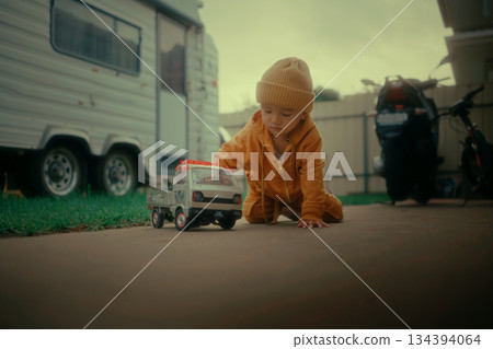 A cheerful child happily playing with a colorful toy truck outdoors during a sunny day A cheerful child happily playing with a colorful toy truck outdoors during a sunny day 134394064