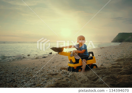 A Young Child Joyfully Playing with a Colorful Toy Truck at Sunset on the Beautiful Beach A Young Child Joyfully Playing with a Colorful Toy Truck at Sunset on the Beautiful Beach 134394070