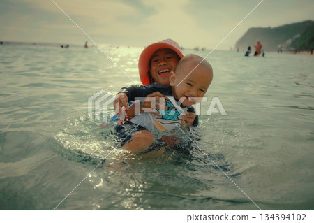 Joyful children play in the water at the beach, enjoying their summer vacation together 134394102