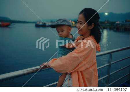 A peaceful Mother and Child by the Water at Dusk during a beautiful evening together 134394107