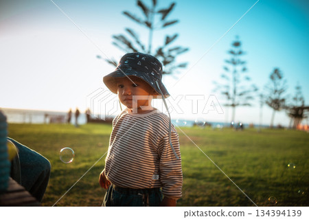 child wearing bucket hat outdoors, child standing in grassy area during sunny family 134394139