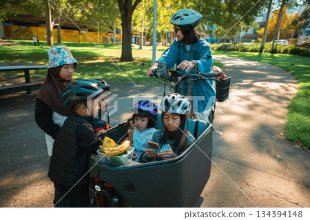 A delightful family outing with kids joyfully enjoying a bike ride in the park 134394148