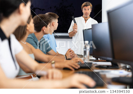 Students of computer courses sit in class near PC, watch to teacher and listen to lecturer 134394530