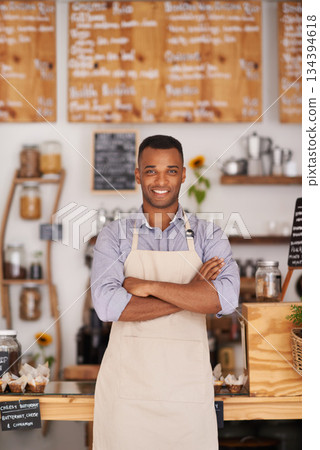 Black man, portrait and barista with arms crossed in cafe with pride for career or job. Waiter, smile and confidence of African person from Nigeria in restaurant, small business and coffee shop. Black man, portrait and barista with arms crossed in cafe with pride for career or job. Waiter, smile and confidence of African person from Nigeria in restaurant, small business and coffee shop. 134394618
