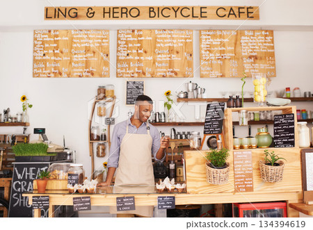 Black man, cafe sign and phone of an entrepreneur with happiness from small business. Coffee shop, mobile and African barista looking on an app with a smile at bakery and restaurant feeling happy Black man, cafe sign and phone of an entrepreneur with happiness from small business. Coffee shop, mobile and African barista looking on an app with a smile at bakery and restaurant feeling happy 134394619