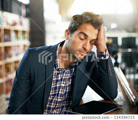Stress, burnout and businessman with a digital tablet in the library while working on a corporate project. Technology, tired and professional male employee with a mobile for a report in the workplace 134394725