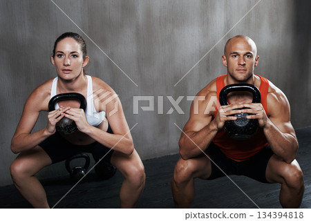 Fitness, people and portrait with kettlebell in squat for weightlifting or exercise together at gym. Serious man and woman lifting weight for strong exercising, power or glutes in training indoors 134394818