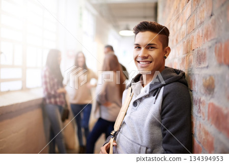 Education, smile and portrait of man in college hallway for studying, learning and scholarship. Future, happy and knowledge with student relax on brick wall for university, academy and campus 134394953
