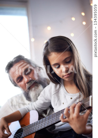 Girl with grandfather, guitar and learning to play, music education and help with creative development. Musician, art and old man helping female kid learn focus and skill on musical instrument 134395059