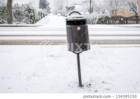 Snow Covered Outdoor Trash Bin Beside Residential Winter Street Snow Covered Outdoor Trash Bin Beside Residential Winter Street 134395150