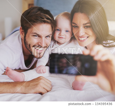 Happy family, parents and selfie of baby on bed in home for love, care and quality time together. Mother, father and newborn child smile for photograph, fun memory and happiness of bonding in bedroom Happy family, parents and selfie of baby on bed in home for love, care and quality time together. Mother, father and newborn child smile for photograph, fun memory and happiness of bonding in bedroom 134395436