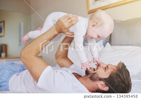 Father, on bed and play with baby girl up in the air or flying daughter and having fun in the bedroom feeling happy. Parent, kid and dad bonding or carefree and excited together in the house 134395458