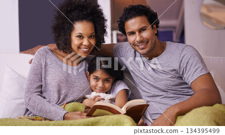 Family, child and reading book portrait in a home for story time on a lounge sofa with a smile. A woman, man or parents and girl child together for development, learning and love with a fantasy 134395499