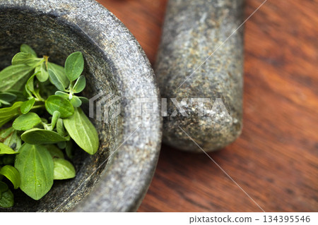 Plant cooking, mortar and pestle for herbs on table top in kitchen. Vegetables, food and equipment for crushing basil leaf, plants or spices for gourmet meal, seasoning and flavor for healthy diet. 134395546