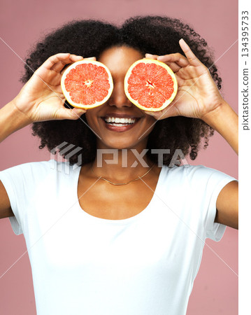 Grapefruit, smile and black woman cover her eyes in studio isolated on a pink background. Natural, fruit and African female model with vegan nutrition, vitamin c or healthy diet, detox or wellness Grapefruit, smile and black woman cover her eyes in studio isolated on a pink background. Natural, fruit and African female model with vegan nutrition, vitamin c or healthy diet, detox or wellness 134395733